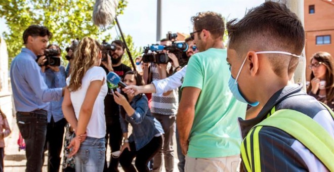 Padres del colegio Juan Carlos I en Seseña, atienden a los medios de comunicación, a su llegada a la recogida del alumnado con máscaras protectoras. /EFE