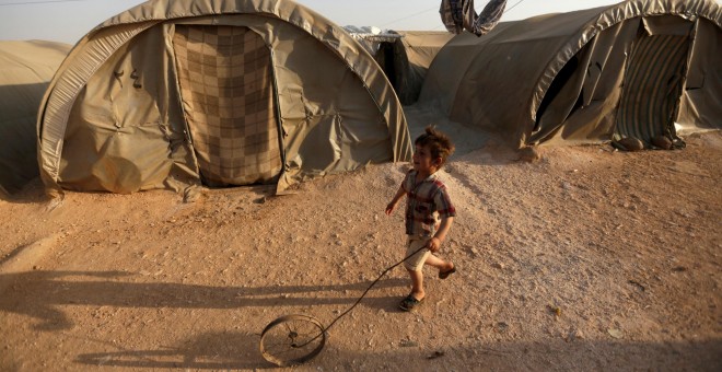 Un niño sirio refugiado juega con una rueda en el campo de Jrzinaz, en la parte sur de Idlib, Siria. REUTERS / Khalil Ashawi