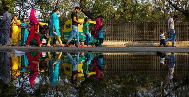 Varios habitantes de Nueva Delhi caminan por una calle encharcada. AFP/Chandan Khanna