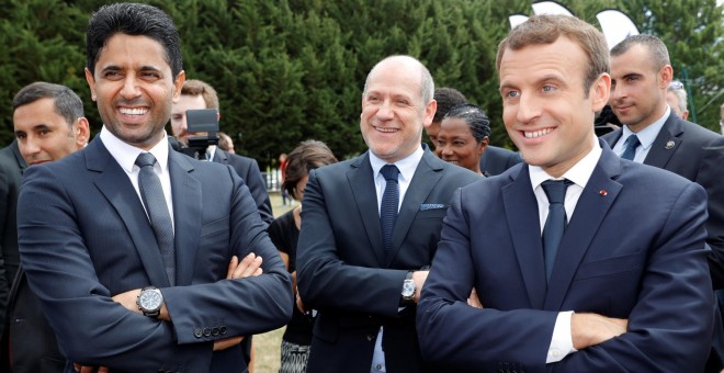 El presidente francés, Emmanuel Macron (d), con el presidente del Paris St Germain, Nasser Al-Khelaifi (i), y el director deportivo del club parisino, Antero Henrique (c), en un acto en un campamento infantil en la localidad  de Moisson, en las afueras de