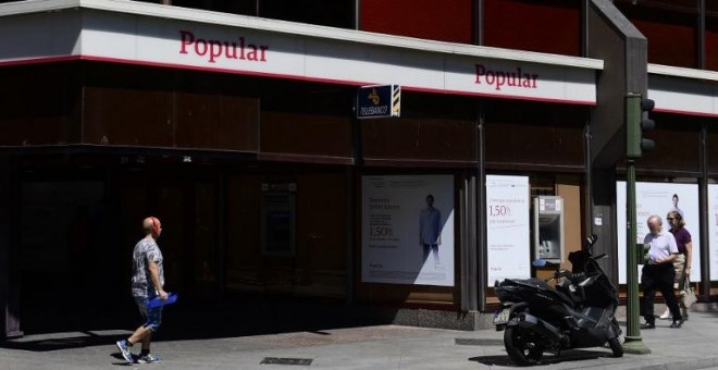 Un hombre pasa junto a una oficina del Banco Popular en  Madrid. AFP/Pierre-Philippe Marcou