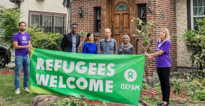 Integrantes de Oxfam sostienen una pancarta de apoyo a los refugiados frente a la casa de la infancia de Trump. / Reuters