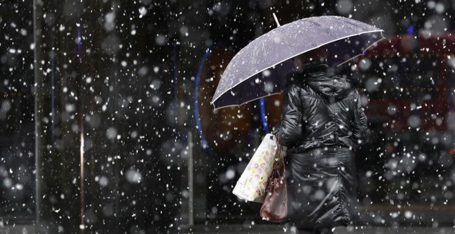 Una mujer camina bajo la nieve en Pamplona. EFE