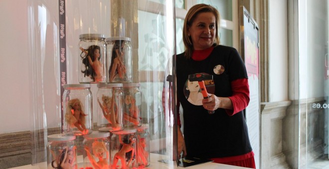 La presidenta de la Diputación de Pontevedra, Carmela Silva, blande un martillo como símbolo para romper las barreras de cristal, junto a una de las piezas, que representa la prostitución. Diputación de Pontevedra