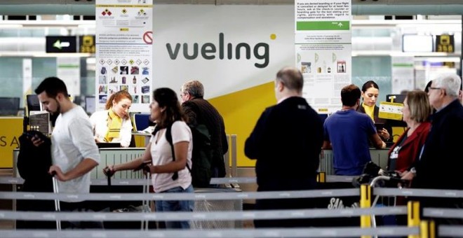 Un grupo de pasajeros ante un mostrador de facturacion de Vueling en el Aeropuerto de Barcelona-El Prat. / EFE