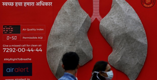 Unas personas pasan junto a un aviso sobre los efectos de la contaminación colocado en el exterior de un hospital en Nueva Delhi. REUTERS/Anushree Fadnavis