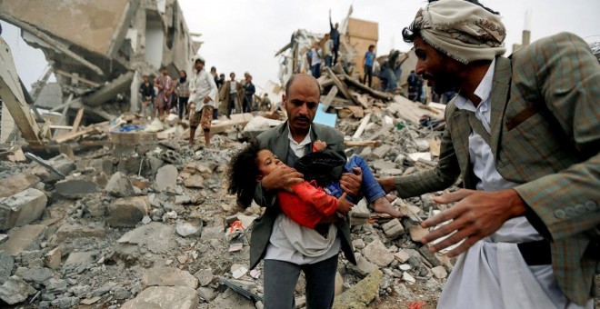 Un hombre lleva en brazos a una niña herida en un bombardeo de la coalición saudí contra Yemen en agosto de 2017. Khaled Abdullah / REUTERS