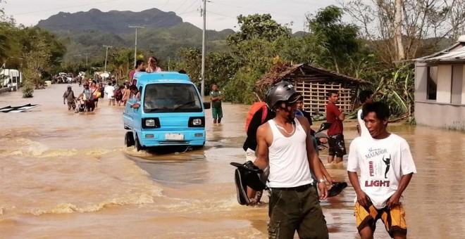 Ormoc (Filipinas), 25/12/2019.- Gente anda por el agua en una carretera inundada el día de Navidad en la ciudad de Ormoc, Filipinas, azotada por el tifón Phanfone, el 25 de diciembre de 2019. El tifón Phanfone (conocido localmente como Ursula) tocó tierra