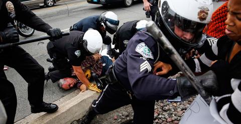 Policías tratan de hacer retroceder a los manifestantes mientras un compañero detiene a un hombre, durante las protestas contra la decisión de la justicia de no acusar a Darren Wilson por la muerte a tiros de Michael Brown. // PATRICK T. FALLON (REUTERS)