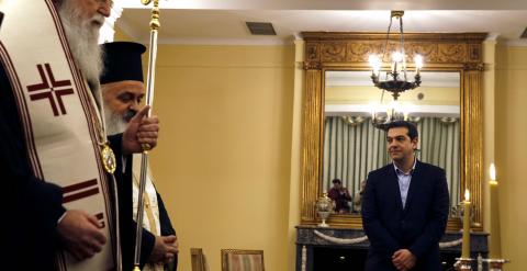 El nuevo primer ministro griego, Alexis Tsipras, observa a los sacerdotes ortodoxos que intervienen en la ceremonia de juramiento de los nuevos miembros del Gobierno heleno. REUTERS/Yannis Behrakis