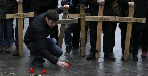 Un hombre coloca en el suelo una vela, junto a las cruces que recuerdan a los muertos en la plaza de Maida, en Kiev, en las revueltas contra el el régimen de Víctor Yanukovich. REUTERS/David W Cerny