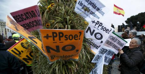 Una mujer coloca unas pancartas en un arbusto durante las Marchas de la Dignidad. REUTERS / Sergio Pérez