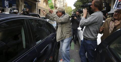 Un preferentista de Bankia junto al coche en el que viaja el exvicepresidente del Gobierno y ex director gerente del FMI, Rodrigo Rato. EFE/Juan Carlos Hidalgo