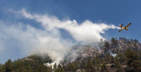 Medios aéreos siguen refrescando hoy el área del incendio forestal declarado ayer cercano a la localidad alicantina de Pego. EFE/NATXO FRANCÉS