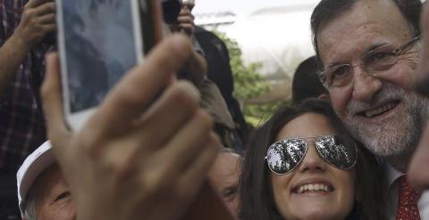 El presidente del PP y del Gobierno, Mariano Rajoy, se fotografía con una simpatizante tras dar un paseo en bicicleta por Madrid Río. EFE/Javier Lizón