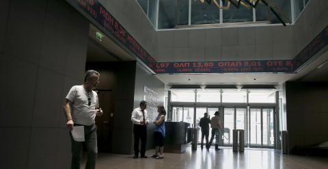 Un hombre camina por la Bolsa de Atenas, cuyos paneles muestran los indicadores del mercado en rojo. REUTERS/Alkis Konstantinidis