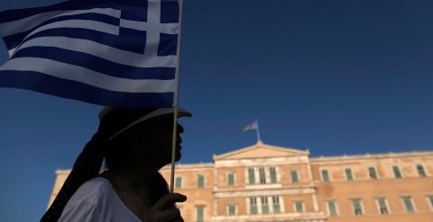 Una manifestante sostiene una bandera griega en frente del Parlamento.-Yannis Kolesidis (EFE)