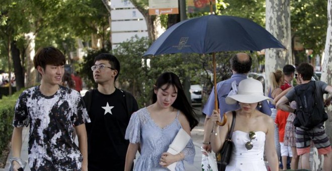 Unas turistas tratan de protegerse del sol con sombreros, paraguas y sombrillas en las cercanias del Museo del Prado en Madrid. /EFE