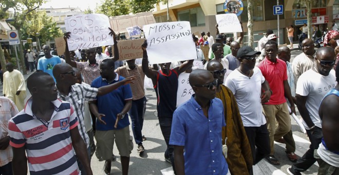 Inmigrantes senegaleses muestran pancartas contra la los Mossos D'esquadra en la manifestació en Salou para protestar por la muerte de un compatriota en una operación contra el 'top manta'. AFP PHOTO / QUIQUE GARCIA