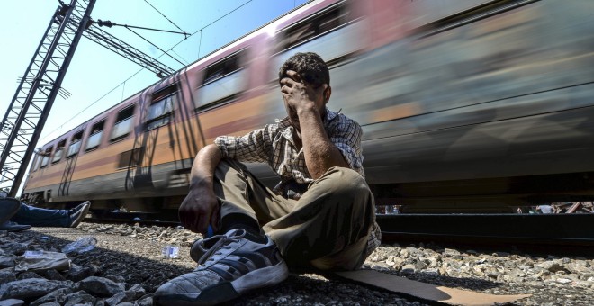 Un inmigrante exhausto y frustrado tras no poder conseguir una plaza en un tren que se dirige a la frontera con Serbia en la estación de tren de Gevgelija (Macedonia) hoy, 13 de agosto de 2015. EFE/Georgi Licovski