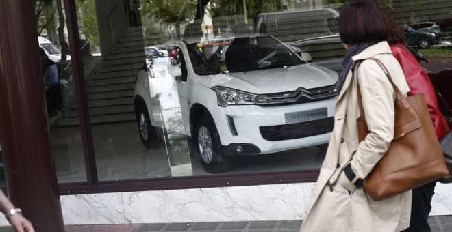 Una mujer pasa junto a un concesionario de automóviles. E.P.