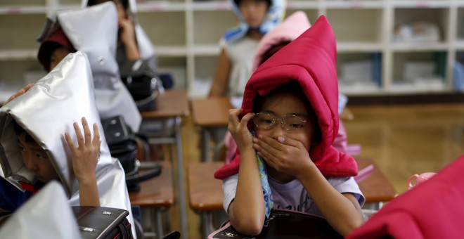 Niños se protegen con capuchas acolchadas en el simulacro de terremoto en un colegio de primaria en Tokio, 1 de septiembre, 2015. REUTERS/Toru Hanai