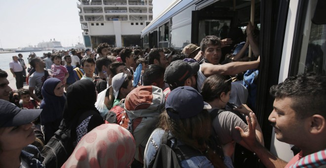 Refugiedos, en su mayoría sirios, tratan de entrar en un autobús tras desembarcar del ferry  'Eleftherios Venizelos' en el puerto ateniense del Pireo.. EFE/EPA/YANNIS KOLESIDIS