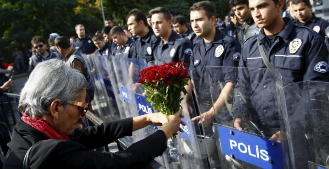 Una manifestante muestra un ramo de flores en la barricada policial deslpegada frente a la concentración en recuerdo de las víctimas del doble atentado suicida en Ankara. REUTERS/Umit Bektas