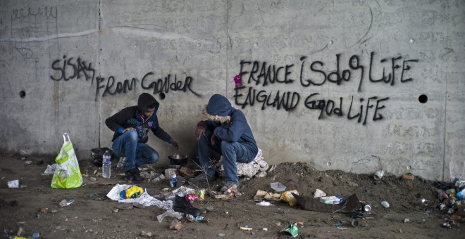 Dos refugiados eritreos cocinan bajo un puente cerca del campamento 'La Jungla', en las afueras de Calais, Francia, hoy 16 de octubre de 2015. Más de 3.000 personas se alojan actualmente en el campamento. EFE/Yoan Valat