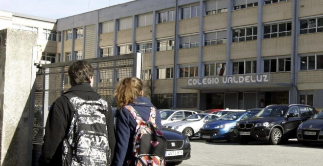 Dos jóvenes pasan por la puerta del colegio Valdeluz. /EFE