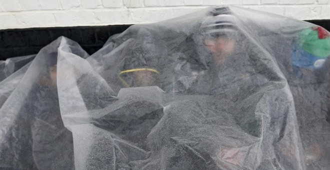 Refugiados intentan calentarse en el puerto de Zeebrugge, en Bélgica, donde pretenden embarcar rumbo a Reino Unido. / EFE