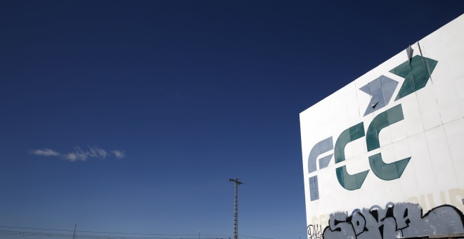 Un tren pasa cerca de un cartel de la empresa de construcción y servicios  FCC, cerca de la localidad madrileña de Tres Cantos. REUTERS/Susana Vera