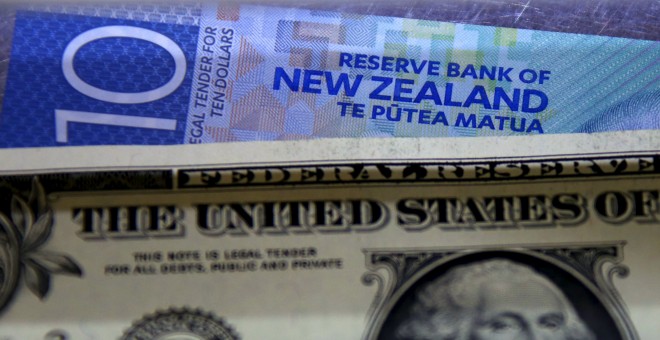 Un billete de diez dólares neozelandeses junto a un dólar estadounidense. REUTERS/David Gray