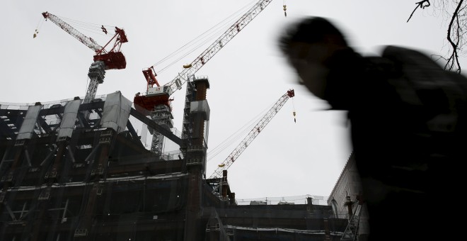 Un hombre camina cerca de las grúas de una edificación en el distrito financiero de Tokio. REUTERS/Yuya Shino