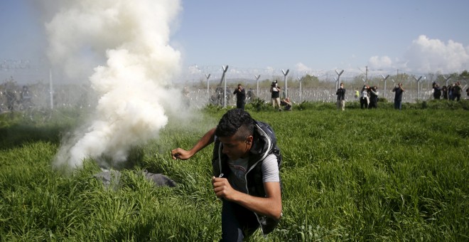 Un refugiado escapa del bote de gas lanzado por la Policía macedonia. REUTERS/Stoyan Nenov