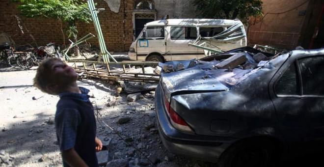 Un niño camina junto a vehículos y edificaciones dañados por un ataque aéreo hoy, jueves 21 de julio de 2016, en Douma (Siria), / EFE