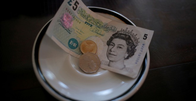 Un billete de cinco libras esterlinas y varias monedas en un platillo en un restaurante en la colonia de Gibraltar. REUTERS/Jon Nazca