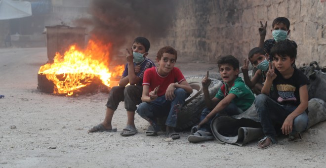 Niños sirios se refugian de los ataques aéreos tras unos neumáticos en llamas para que el humo reduzca la visibilidad y sea más complicado bombardearlos/Alepo Media Center y Syria Campaign