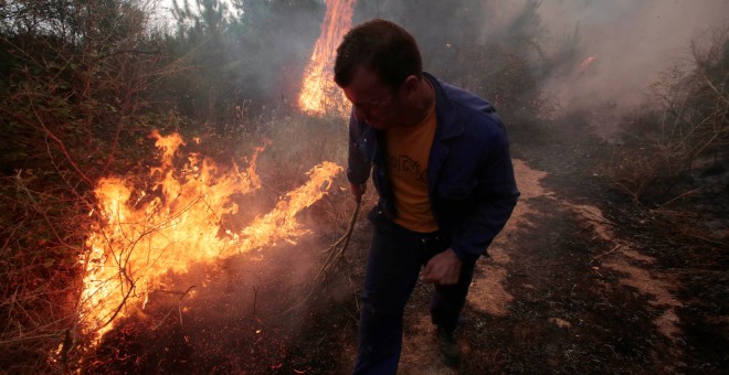 Un hombre apaga las llamas de incendio de Arbo, en Galicia.- REUTERS