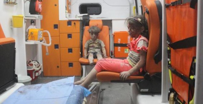 Omran Daqneesh, de cinco años, junto a su hermana en la ambulancia tras ser rescatados de un bombardeo en Alepo. REUTERS