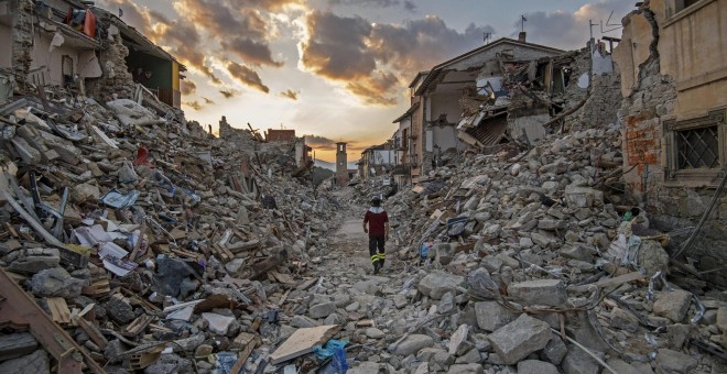 Un bombero pasa entre los escombros de los edificios hundidos en Amatrice tras el terremoto. - EFE