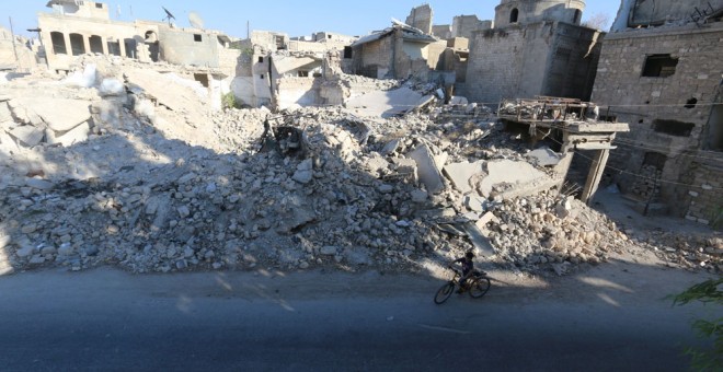 Un niño monta en bicicleta cerca de los escombros de los edificios dañados en el distrito de Al Maadi de Alepo, (Siria).- Abdalrhman Ismail (REUTERS)