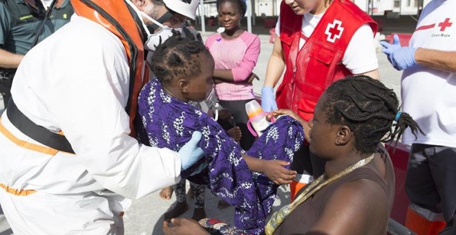 Una mujer con su bebé es ayudada a bajar en el puerto de Motril (Granada) donde han sido trasladados después de que Salvamento Marítimo haya rescatado hoy a un total de 34 personas cuando viajaban en una patera a 7,5 millas al sur de la isla de Alborán. E