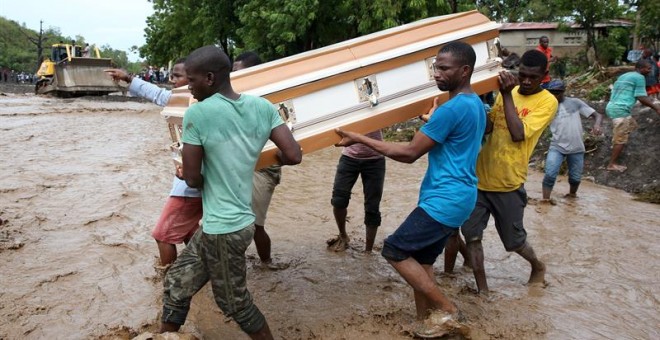 Varios hombres cargan un ataúd e intentan cruzar el río La Digue, en Petit Goave (Haití). - EFE