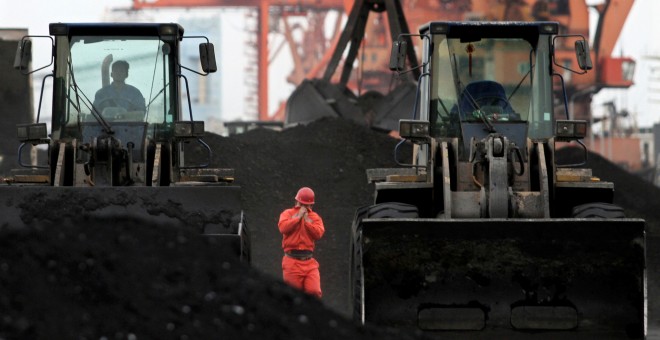 Un trabajador chino entre las excacvadoras que se utiliza para mover el carbón importado de Corea del Norte, en el puerto de Dandong. REUTERS/Stringer