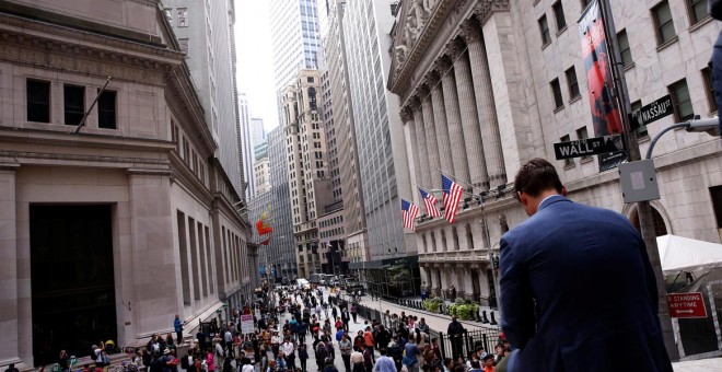 Un hombre sentado sobre un muro de mármol en frente del New York Stock Exchange, EEUU. / REUTERS