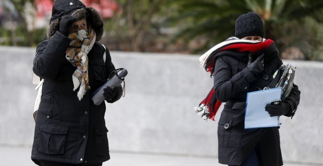 os mujeres se abrigan debido al frío y al viento durante la mañana de este jueves en Valencia/ EFE