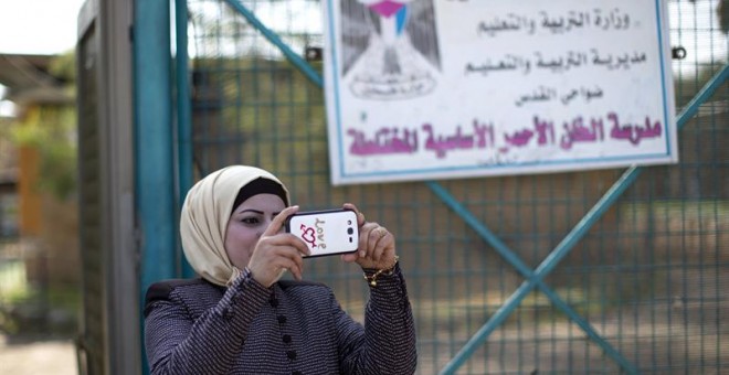 Una mujer hace una foto en el colegio de la comunidad de Jan al Ahmar. EFE/Atef Safadi