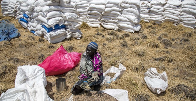 Una mujer recoge granos dejados en el suelo después de una distribución de alimentos en Sudán del Sur. AFP/Albert González Farran