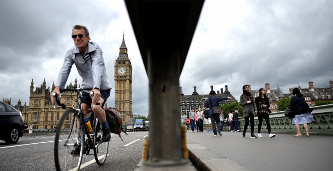 Un ciclista y varios peatones pasan junto a las barreras instaladas en el Puente de Westminster, en Londres. REUTERS/Hannah McKay